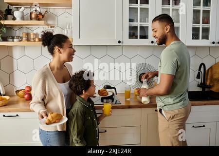 Uomo, donna e ragazzo condividono momenti di gioia in cucina. Foto Stock