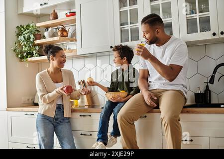 Famiglia afroamericana che si gusta un pasto sul bancone della cucina insieme. Foto Stock