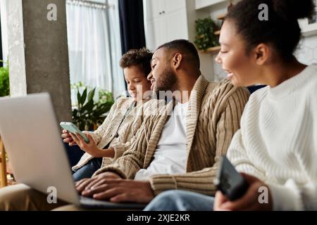 Famiglia afroamericana impegnata con un laptop sul divano. Foto Stock