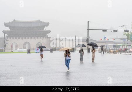 Seoul, Corea del Sud. 18 luglio 2024. Le persone che hanno degli ombrelli per proteggersi dalla pioggia camminano attraverso la piazza centrale di Gwanghwamun a Seoul. Il 18 luglio, i torrenziali hanno toccato la più ampia area di Seoul e le regioni adiacenti, portando all'evacuazione dei residenti a causa dei corsi d'acqua gonfiati e della chiusura delle autostrade, un ponte a Seoul e i vicini servizi della metropolitana. Credito: SOPA Images Limited/Alamy Live News Foto Stock