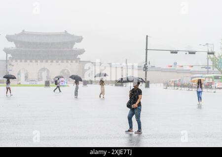 Seoul, Corea del Sud. 18 luglio 2024. Le persone che hanno degli ombrelli per proteggersi dalla pioggia camminano attraverso la piazza centrale di Gwanghwamun a Seoul. Il 18 luglio, i torrenziali hanno toccato la più ampia area di Seoul e le regioni adiacenti, portando all'evacuazione dei residenti a causa dei corsi d'acqua gonfiati e della chiusura delle autostrade, un ponte a Seoul e i vicini servizi della metropolitana. Credito: SOPA Images Limited/Alamy Live News Foto Stock