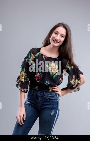 Una giovane donna sicura di sé con un outfit elegante si posa felicemente, mostrando femminilità moderna e vivacità giovanile Foto Stock