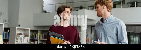 Due uomini coinvolti in una discussione accademica in una biblioteca. Foto Stock