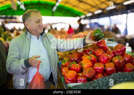 Uomo che acquista peperoni in gregrocery Foto Stock