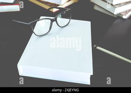 Occhiali da lettura neri, notebook bianchi e neri con spazio per il testo sul desktop Foto Stock