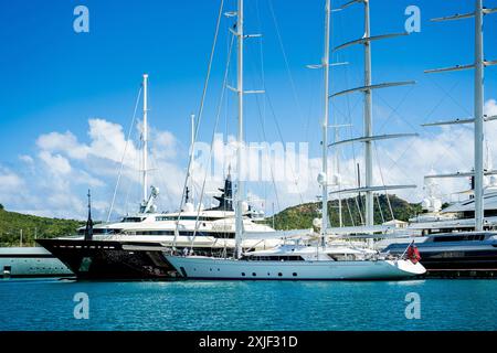 Diversi mega yacht e superyacht bellissimi e immacolati al molo di English Harbour, una famosa isola caraibica di Antigua conosciuta per la stagione degli yacht e le regate Foto Stock