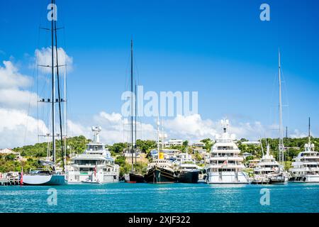 Diversi mega yacht e superyacht bellissimi e immacolati al molo di English Harbour, una famosa isola caraibica di Antigua conosciuta per la stagione degli yacht e le regate Foto Stock