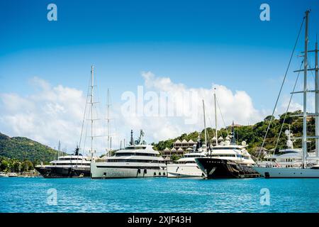 Diversi mega yacht e superyacht bellissimi e immacolati al molo di English Harbour, una famosa isola caraibica di Antigua conosciuta per la stagione degli yacht e le regate Foto Stock