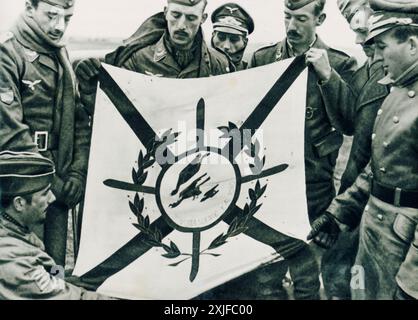 Una fotografia mostra i soldati volontari spagnoli, noti come i cacciatori spagnoli (Jäger), che tengono la loro bandiera in un aeroporto durante l'operazione Barbarossa nel 1941. Il corrispondente di guerra tenente Mittler si trova all'estrema destra. Questi volontari unirono le forze tedesche per combattere contro le truppe sovietiche sul fronte orientale durante la seconda guerra mondiale. Foto Stock