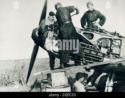 Una fotografia mostra i volontari spagnoli nell'esercito tedesco che eseguono la manutenzione del motore di un aereo durante l'operazione Barbarossa nel 1941. Questi volontari unirono le forze tedesche per combattere le truppe sovietiche sul fronte orientale, guidate dalla posizione anticomunista della Spagna e dal sostegno del generale Franco alla Germania nazista durante la seconda guerra mondiale. Foto Stock