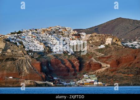 Città di Oia sul bordo della scogliera sopra la caldera, con il porto di Ammoudi sotto. Santorini, Isole Cicladi, Grecia. Foto Stock