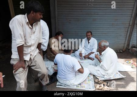 Uomini che giocano a carte in una strada a nuova Delhi, in India Foto Stock