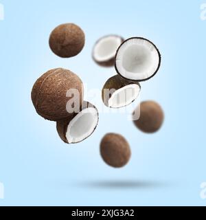 Molte noci di cocco in aria su sfondo azzurro Foto Stock
