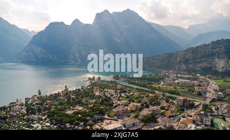 Torbole, Lago di Garda, Italia - 18 luglio 2024: Veduta aerea di Torbole sul Lago di Garda in Italia. In primo piano è possibile vedere il villaggio con le sue case e le sue strade. Il lago si estende maestosamente in lontananza, circondato da alte montagne *** Luftaufnahme von Torbole am Gardasee in Italia. Im Vordergrund sieht man das Dorf mit seinen Wohnhäusern und Straßen. Der SEE erstreckt sich majestätisch in Die Ferne, umgeben von hohen Bergen Foto Stock