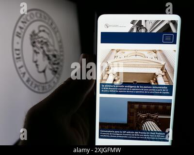 Persona che detiene un cellulare con pagina web del Banco Central de la Republica Argentina (BCRA) davanti al logo. Messa a fuoco al centro del display del telefono. Foto Stock