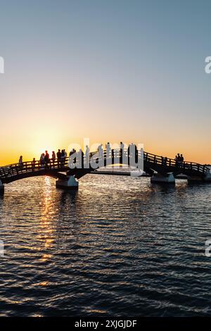 Romantico tramonto a Lefkada o sull'isola greca di Lefkas, sul Mar Ionio vicino a Preveza. Sagoma della gente sul ponte, vacanze estive Foto Stock