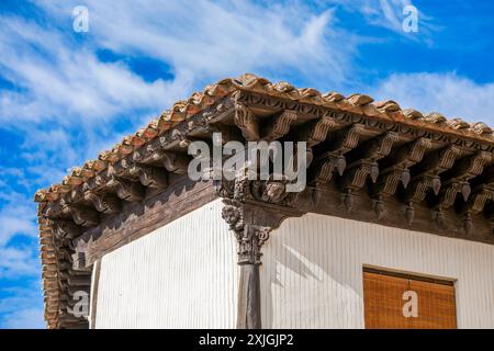 Dettaglio architettonico di un cornicione in legno intagliato con molti dettagli e una colonna con sculture sulla facciata di una casa nel centro storico di Atienza, GU Foto Stock