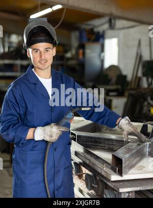 Durante la fabbricazione del prodotto, il dipendente MAN lavora con una saldatrice Foto Stock