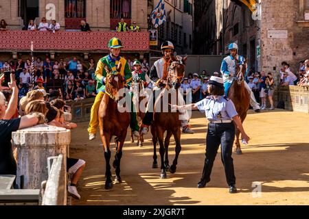 I fantini che indossano i loro colori Contrada si avvicinano alla linea di partenza per la prima delle tre gare di prova mattutine, il Palio, Siena, Toscana, Italia. Foto Stock