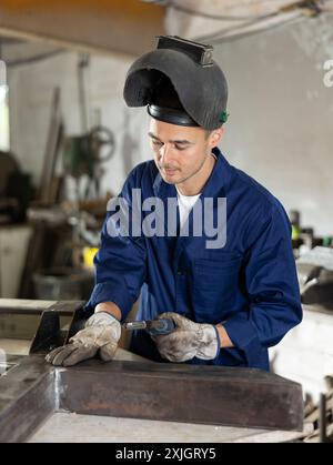 Durante la fabbricazione del prodotto, il dipendente MAN lavora con una saldatrice Foto Stock