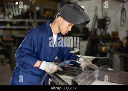 Durante la fabbricazione del prodotto, il dipendente MAN lavora con una saldatrice Foto Stock