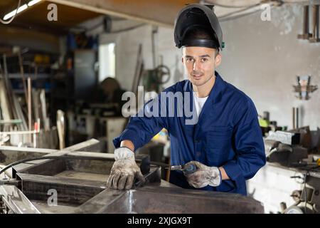 Durante la fabbricazione del prodotto, il dipendente MAN lavora con una saldatrice Foto Stock