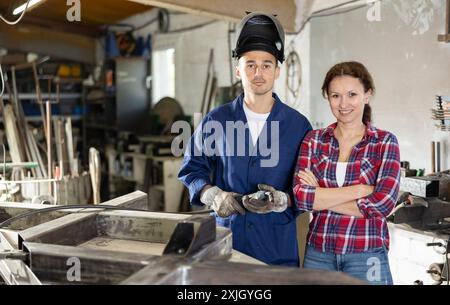 L'uomo allena la donna a collegare i binari di ferro con la saldatrice. Foto Stock