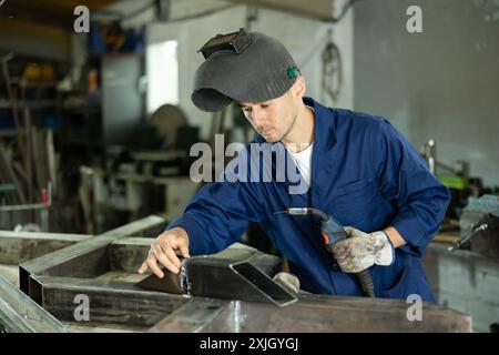 Durante la fabbricazione del prodotto, il dipendente MAN lavora con una saldatrice Foto Stock