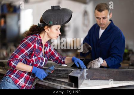 L'uomo allena la donna a collegare i binari di ferro con la saldatrice. Foto Stock