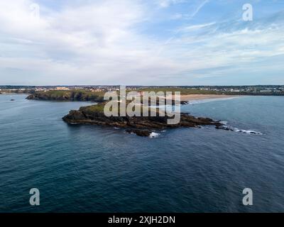 Il promontorio con un piccolo edificio in cima si protende verso l'oceano, separando due spiagge, con la città di newquay sullo sfondo Foto Stock