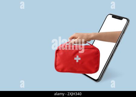 Telefono cellulare e mano del medico con kit di pronto soccorso su sfondo azzurro. Banner per il design Foto Stock