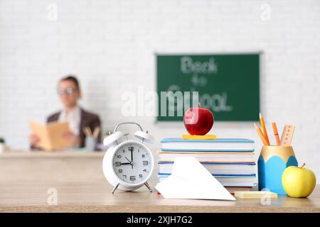 Mele, libri, sveglia e pialla di carta sulla scrivania in classe. Ritorno al concetto di scuola Foto Stock