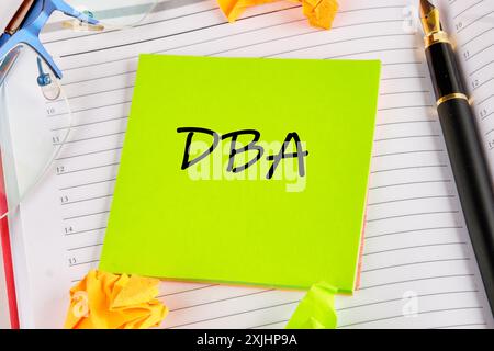 Lettere DBA o Doctor of Business Administration su un adesivo verde chiaro posizionato sul notebook Foto Stock