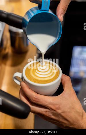 Il latte viene versato in un caffè durante il processo di preparazione. Foto Stock