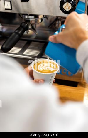 Il latte viene versato in un caffè durante il processo di preparazione. Foto Stock