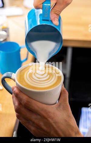 Il latte viene versato in un caffè durante il processo di preparazione. Foto Stock