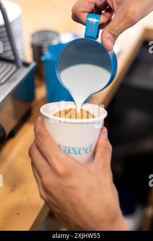 Il latte viene versato in un caffè durante il processo di preparazione. Foto Stock