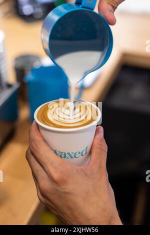 Il latte viene versato in un caffè durante il processo di preparazione. Foto Stock