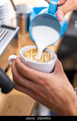 Il latte viene versato in un caffè durante il processo di preparazione. Foto Stock