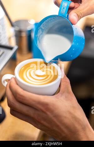 Il latte viene versato in un caffè durante il processo di preparazione. Foto Stock