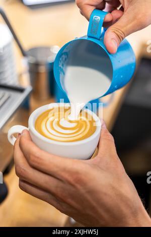 Il latte viene versato in un caffè durante il processo di preparazione. Foto Stock