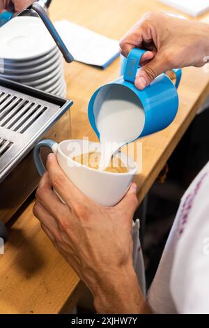 Il latte viene versato in un caffè durante il processo di preparazione. Foto Stock