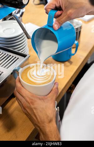 Il latte viene versato in un caffè durante il processo di preparazione. Foto Stock