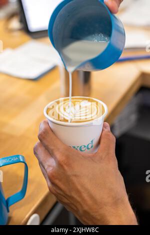 Il latte viene versato in un caffè durante il processo di preparazione. Foto Stock