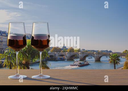 Serata romantica sulla Senna a Parigi con due bicchieri di vino rosso al tramonto con vista sull'iconica Torre Eiffel, che proietta un caldo bagliore sulla tran Foto Stock