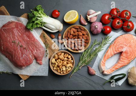 Composizione piatta con carne fresca e altri prodotti per un'alimentazione equilibrata sulla tavola nera Foto Stock