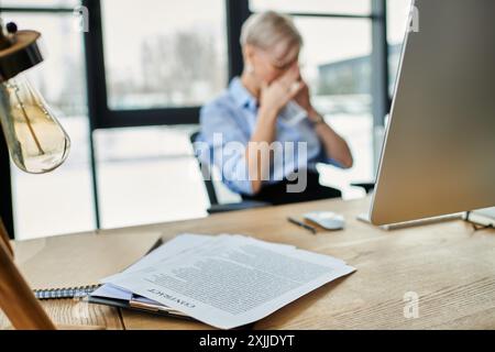 Donna d'affari di mezza età con capelli corti, concentrata sul lavoro alla scrivania con computer in ufficio. Foto Stock