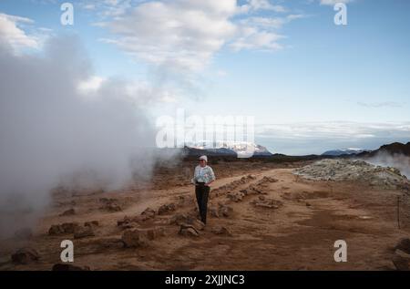 Le donne turistiche camminano su ghiaia arancione nell'area geotermica di Myvatn Foto Stock