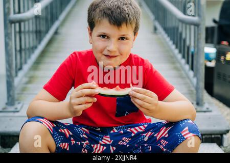 Ragazzo che si gode l'anguria sui gradini durante l'estate. Foto Stock