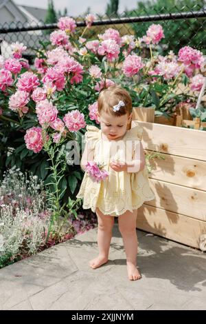 Bimba che esplora i fiori nel giardino, godendosi una giornata estiva Foto Stock